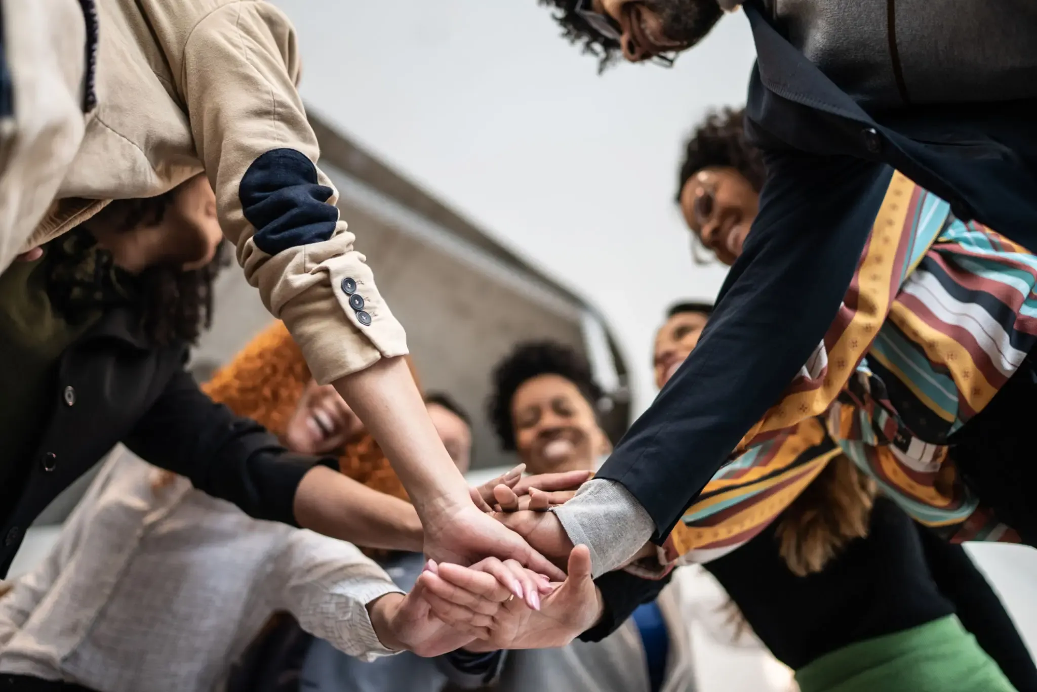 A diverse group joining hands in unity and teamwork.